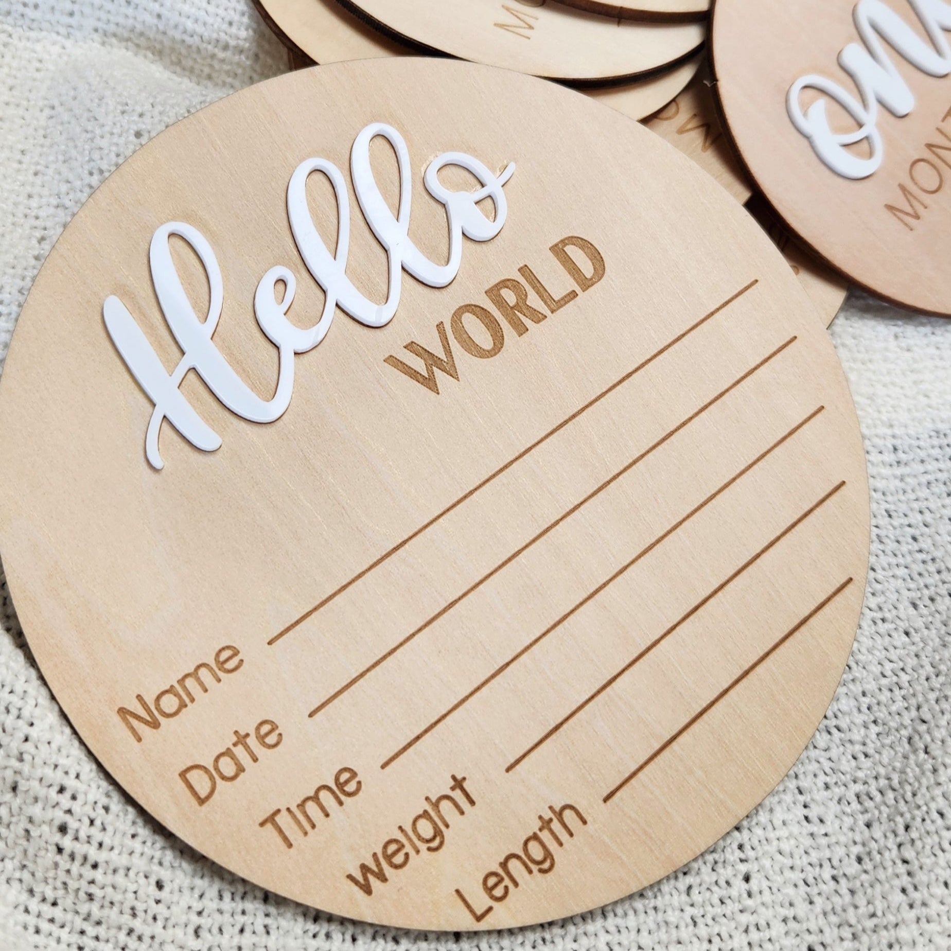 Round wooden card with 'Hello World' text and blank lines for personalization on a textured surface.